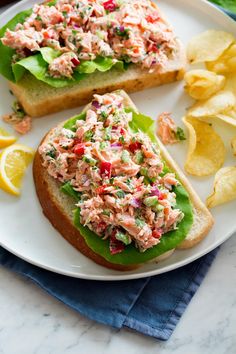 two halves of toasted bread with crab salad on them and chips next to it