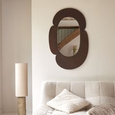 a living room with a white couch, mirror and lamp on the wall above it