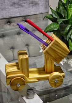 two toothbrushes are sitting in a wooden toy car next to a potted plant