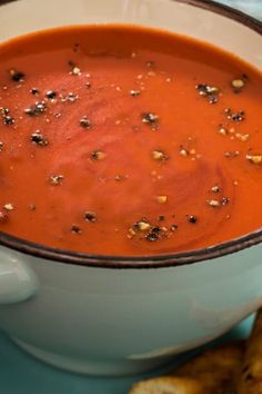 a bowl of tomato soup with bread on the side