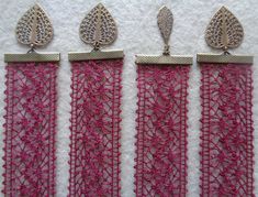 three pieces of pink lace with silver accents on white fabric, each piece has an intricate design in the middle