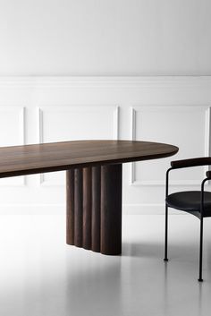 a wooden table sitting next to a black chair in a room with white paneling