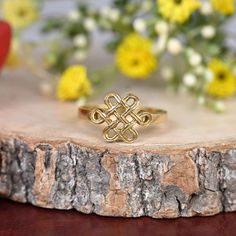 a gold ring sitting on top of a piece of wood next to some yellow flowers