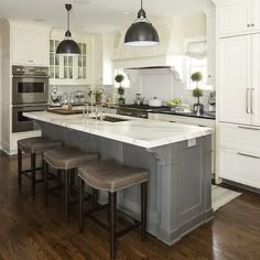 a large kitchen with an island in the middle and three stools next to it