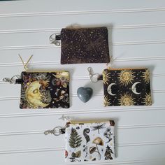 three zippered pouches hanging from hooks on a white wall, each with an image of the moon and stars