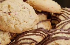 cookies with chocolate drizzled on them sitting in a pile next to each other