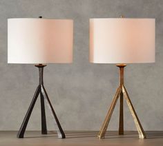 two lamps sitting next to each other on top of a wooden table with a white lamp shade