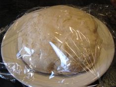 an uncooked round bread sitting on top of a plastic wrapper wrapped in plastic