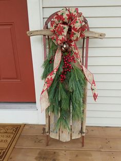 a wooden sleigh decorated with evergreen and red berries is sitting on the front porch