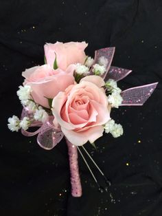 a bouquet of pink roses and baby's breath flowers on a black cloth background