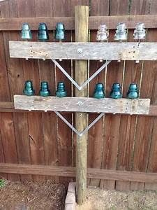 a wooden sign with many blue glass jars on it's sides and a fence in the background