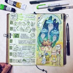 an open notebook with drawings and markers on it