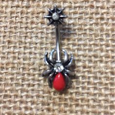 a spider belly ring with a red bead on the bottom and a black jewel in the middle