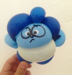 a hand holding a blue and white toy with an angry expression on it's face