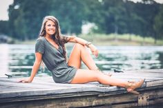 a beautiful woman sitting on top of a wooden dock