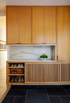 a kitchen with wooden cabinets and black tile flooring, along with shoes on the counter