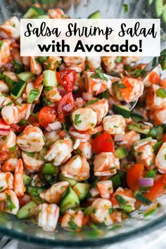 shrimp salad with avocado and tomatoes in a glass bowl on top of a table