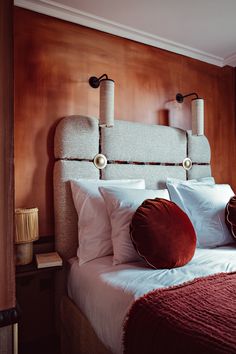 a bed with pillows and two lamps on the headboard