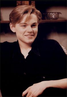 a young man sitting in front of a shelf with a basket on it's back