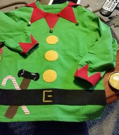 a green christmas sweater sitting on top of a wooden table