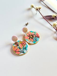 These unique hand painted earrings are the perfect addition to your summer look! They are one of a kind - so look and feel unique when you wear these cuties. Made with polymer clay and painted in fun, vibrant colors, they come in two options: a pink and gold line stud or a green check stud. Add a pop of playfulness to any outfit! Polymer Clay Handmade & Painted Fun back design Surgical steel stud post Colorful Hand-painted Drop Earrings, Playful Hand Painted Resin Earrings, Colorful Hand Painted Drop Earrings, Hand Painted Resin Earrings In Whimsical Style, Hand Painted Colorful Earrings For Gifts, Colorful Hand Painted Earrings As Gift, Colorful Hand Painted Earrings For Gift, Whimsical Hand Painted Resin Earrings, Handmade Trendy Pink Flower Earrings