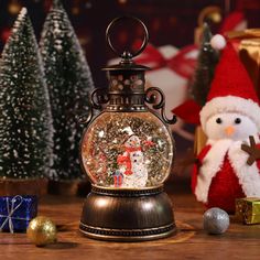 a snow globe sitting on top of a wooden table next to christmas trees and presents