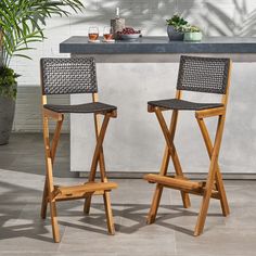 two chairs sitting next to each other in front of a counter with potted plants