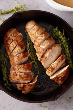 sliced pork in a cast iron skillet with herbs