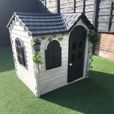 a small white dog house with black doors and windows