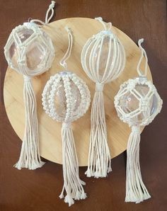 three white crocheted lanterns on a wooden plate with string and beads hanging from the sides