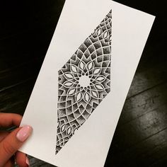 a person holding up a piece of paper with an intricate design on it