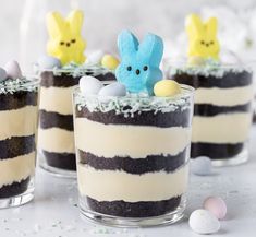 three desserts in glass cups with peep holes on the top and easter decorations around them