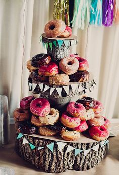 a three tiered cake with donuts on top and other pastries around it