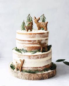 a three tiered cake decorated with deer and pine trees