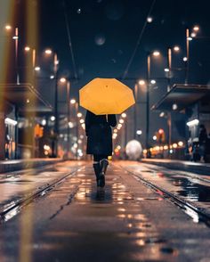 a person walking down the street with an umbrella in their hand, at night time