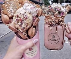 two people holding up cups filled with ice cream and cookies