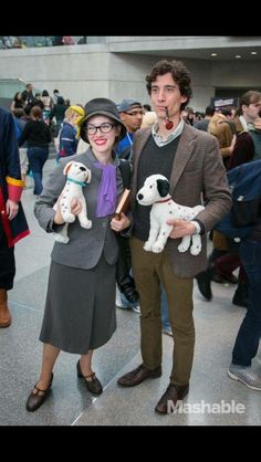 a man and woman standing next to each other holding puppies in their hands at an event