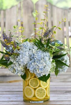 a vase filled with lots of flowers and lemon slices on top of a wooden table