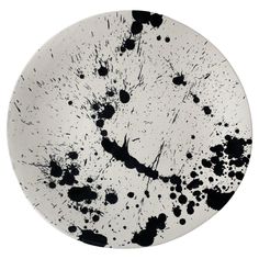 a black and white plate with splattered paint on the bottom, in front of a white background