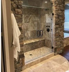 a walk in shower sitting next to a window with a glass door and stone wall