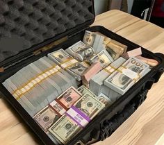 a suitcase filled with money sitting on top of a wooden table