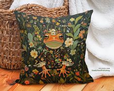 a decorative frog pillow sitting on top of a wooden floor next to a wicker basket