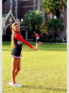 two cheerleaders in black and red uniforms are doing tricks on the grass outside