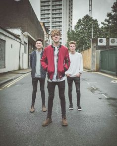 three young men standing in the middle of an empty street