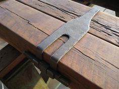 a large knife sitting on top of a wooden table next to a piece of wood