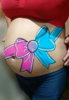 a pregnant woman with pink and blue bows on her belly is wearing a red top