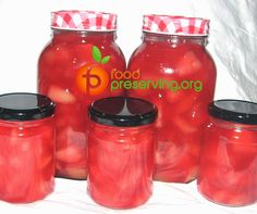 red jars with black lids are lined up on a white tablecloth that says food preserving org