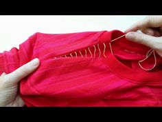 someone is stitching the thread on a red t - shirt that has been folded over