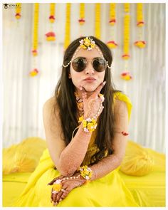 a woman in a yellow dress with flowers on her head and hands near her face