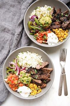 two bowls filled with meat, rice and veggies on top of a table